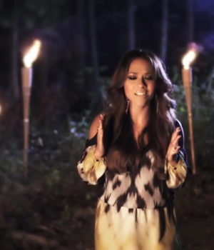 A woman holding candles in the woods at night.