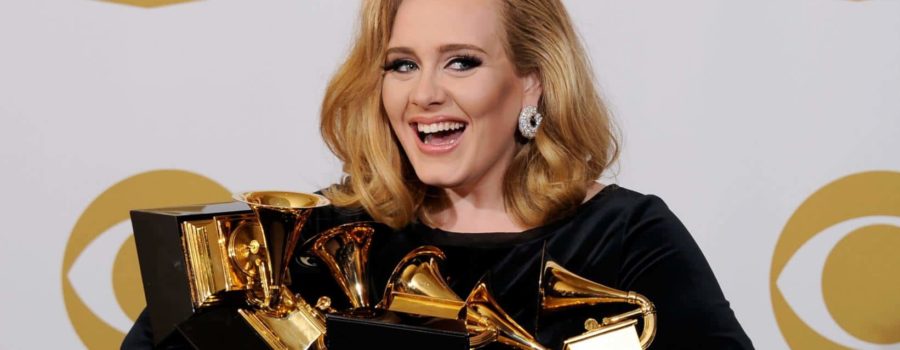 A woman holding her grammy award in front of the camera.