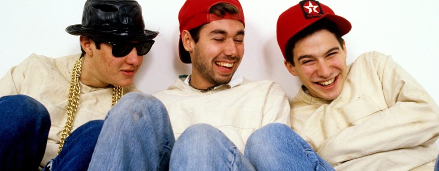 Three young men sitting on the ground wearing hats.
