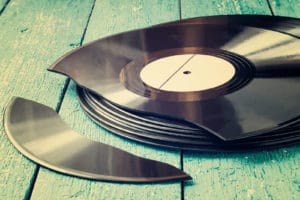 Stack of old vinyl records on a blue wooden background one record broken. Toned photo