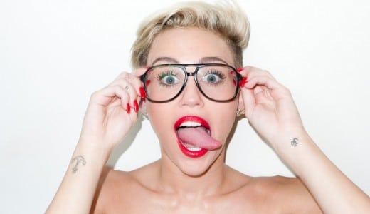 Miley Cyrus sticking out her tongue with glasses on