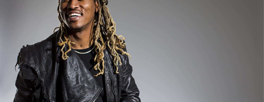 A man with dreads is smiling and wearing a leather jacket.