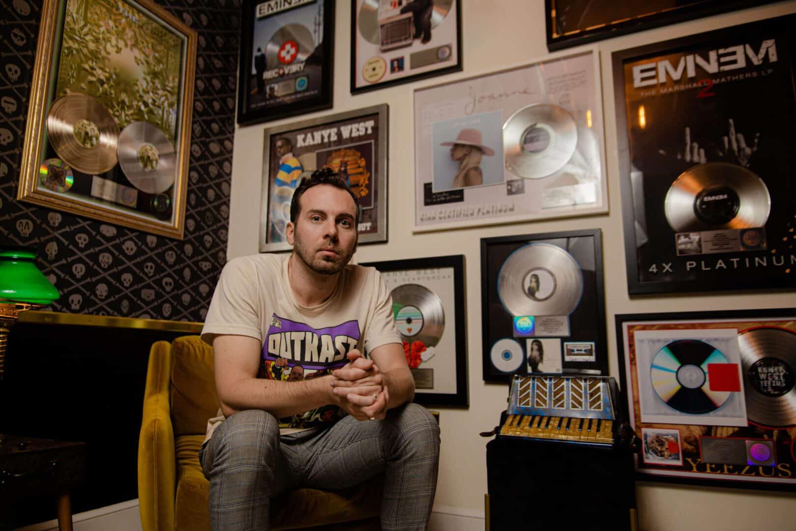 A man sitting in front of many records on the wall.
